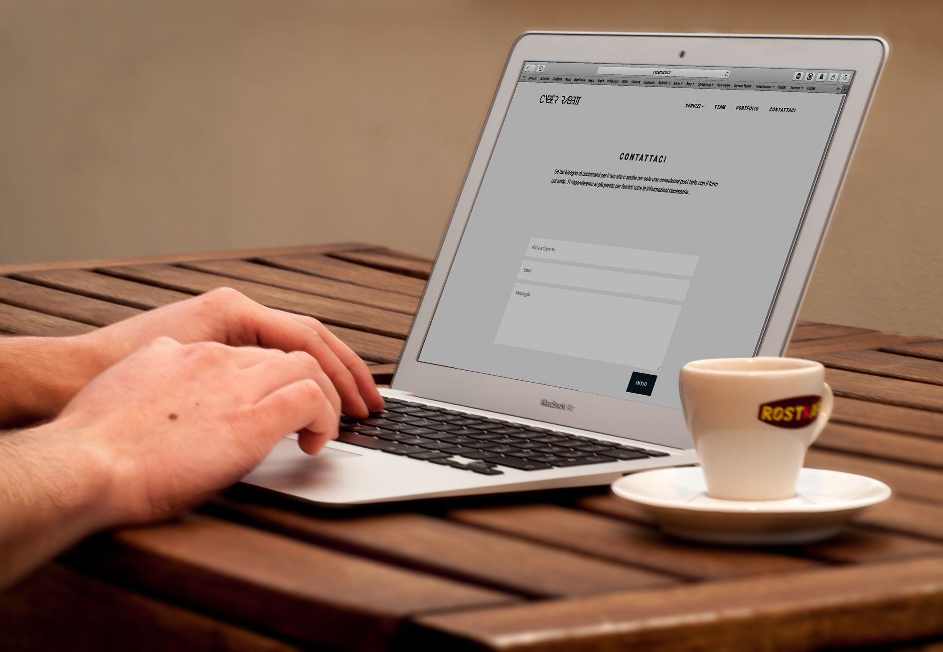 human using laptop beside teacup on the wooden table