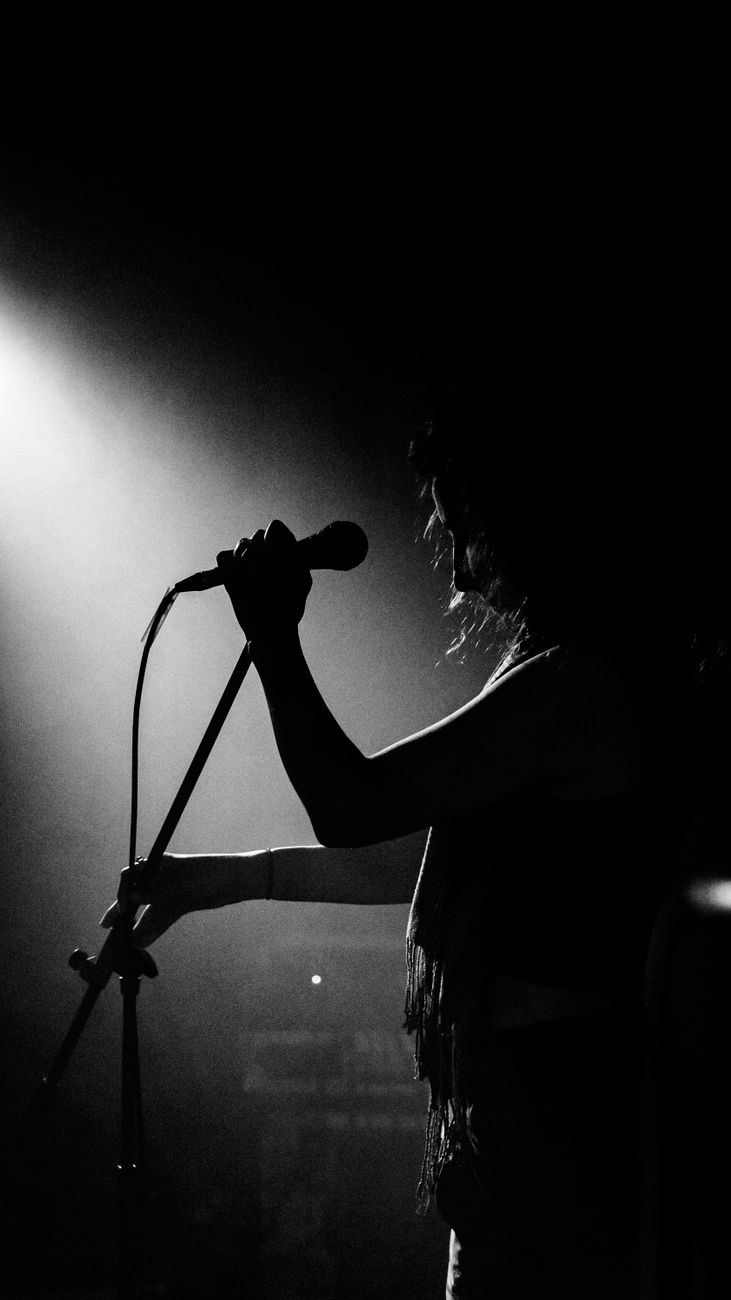 singer standing with microphone in darkness